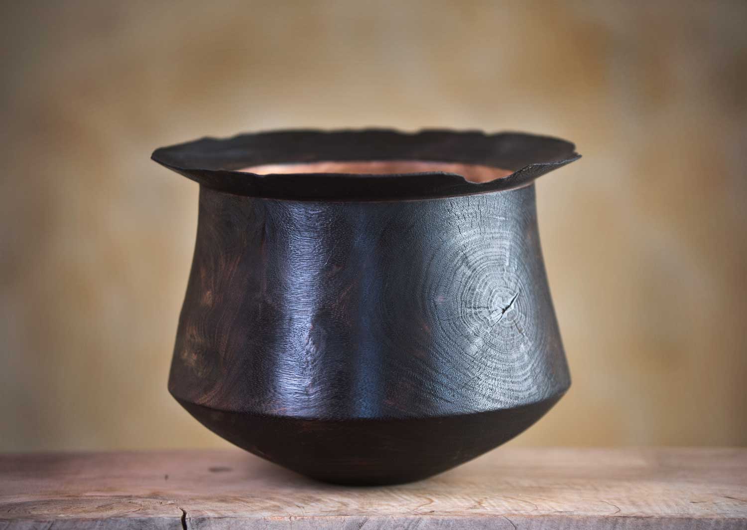Burnt wood vessel with blackened, eroded exterior and contrasting natural wood interior.