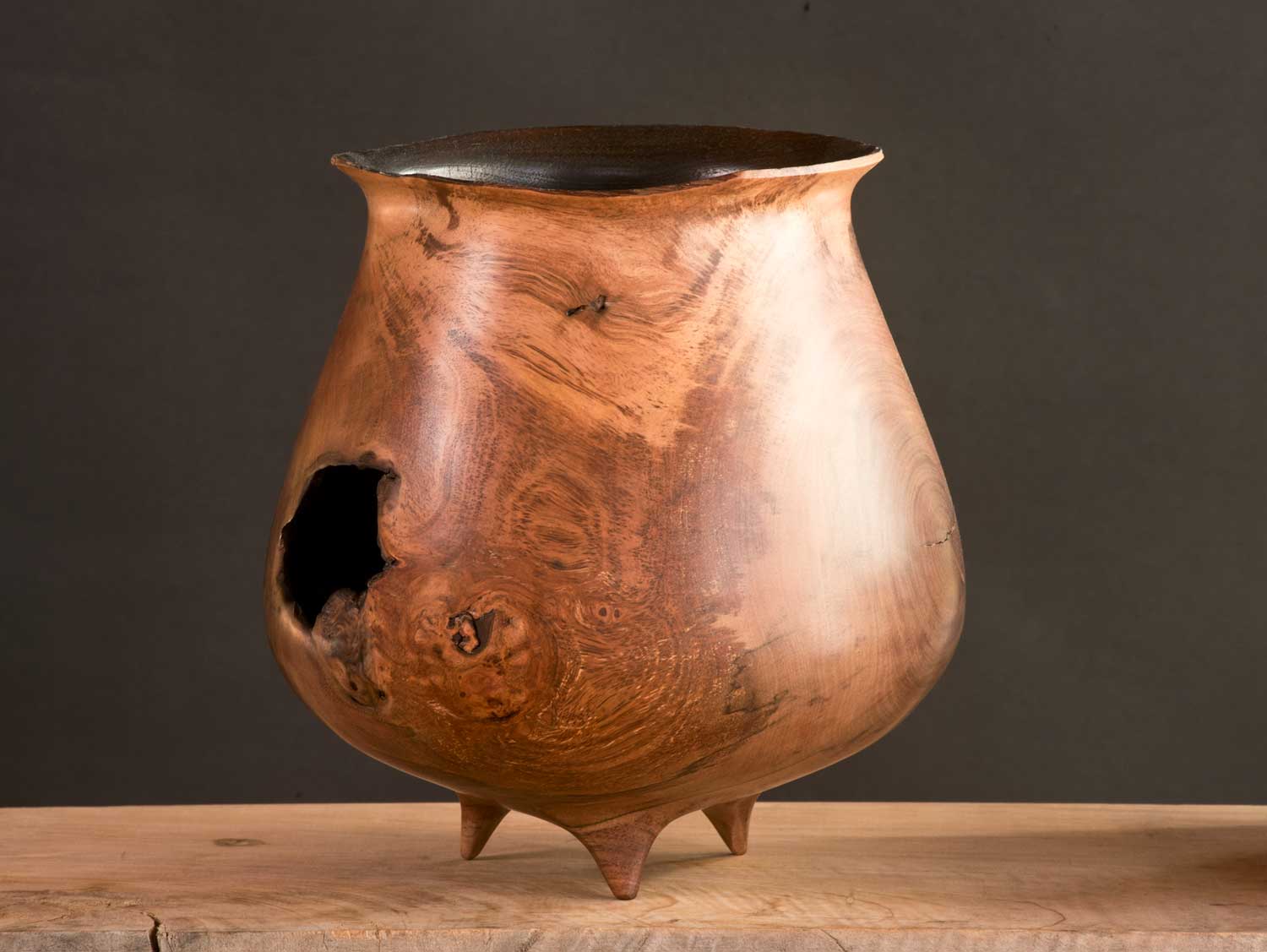 Wooden-Art-Vessel-No702 Blackened wooden vessel with broken rim and large hole in side, resembling a scorched cauldron.